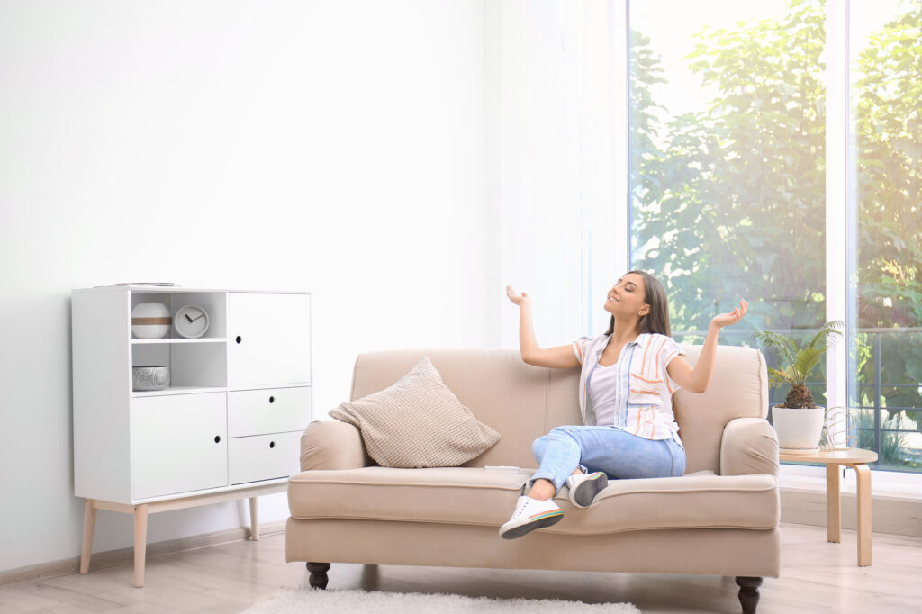 A woman at home relaxing thanks to her newly-repaired HVAC unit.